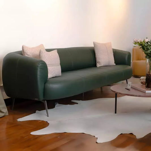 Sofá verde em couro natural com design curvo e almofadas claras